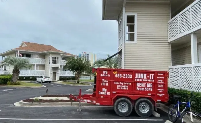 A Junk It mobile dumpster parked off-street beside a North Myrtle Beach condominium building