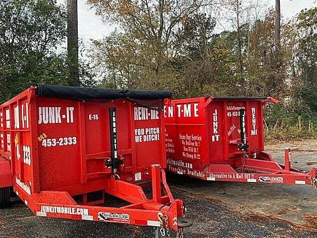 Two Junk It mobile dumpsters staged together on a cleared lot
